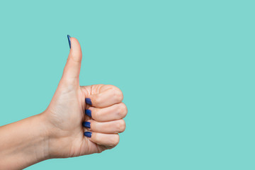 Woman making like gesture putting thumb up. Female hand with modern blue gel polish manicure...