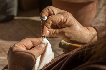 Mujer utilizando una aguja y un dedal para coser una vieja prenda