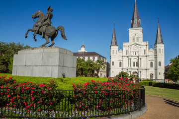 Fototapeta na wymiar St. Louis Cathedral, Jackson Square, Louisiana, United States. Color horizontal image with Andrew Jackson statue in foreground with red flowers.