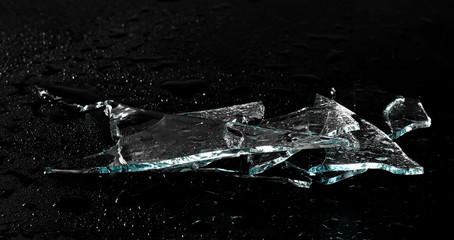 Broken glass pile pieces with water droplets isolated on black background and texture