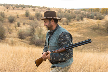 Hunter with a hat and a gun in search of prey in the steppe	