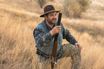 Hunter with a hat and a gun in search of prey in the steppe	