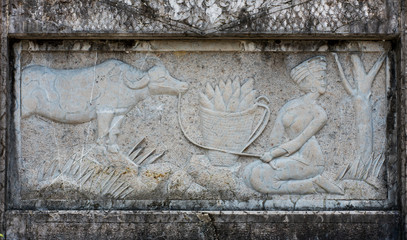 Stone relief panel showing tradional Chinese scene. Woman with cow and corn cobs.