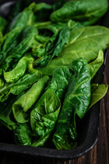 Leaves of spinach. Fresh organic spinach on a wooden table. Vegan food, healthy food. Dark rustic style photo.