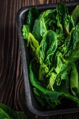 Leaves of spinach. Fresh organic spinach on a wooden table. Vegan food, healthy food. Dark rustic...