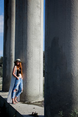 Silhouette of young redhead woman in hat and jeans near the column.