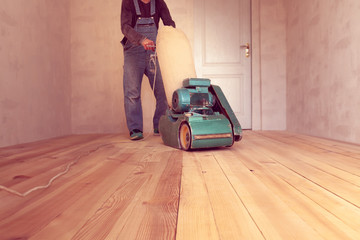 carpenter works by electric grinding wood machine in a room