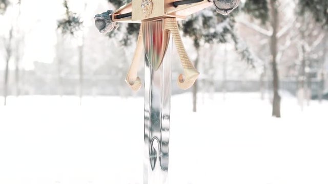 mysterious picture of silver royal sword standing alone in the snow, abandoned weapon as symbol of grave and grief about the dead warrior, brilliant blade of pure sword, movie for the film, no people