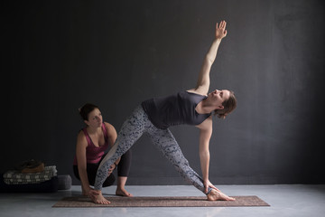 Yoga class instructor and beginner making asana exercises.