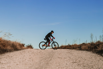 Fototapeta na wymiar Cyclist Riding the Bike Down Rocky Hill at Sunset. Extreme Sport Concept.