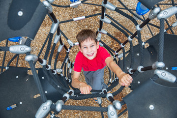 child having fun on outdoor playground.boy climbs up the Jungle Gym