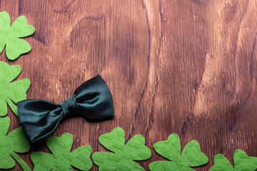 Green clover leaf and bowtie on wooden background