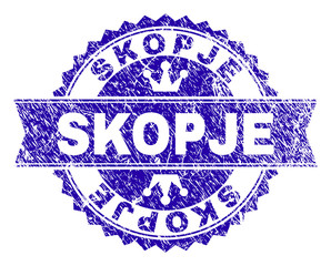 SKOPJE rosette stamp seal imitation with grunge style. Designed with round rosette, ribbon and small crowns. Blue vector rubber watermark of SKOPJE label with grunge texture.