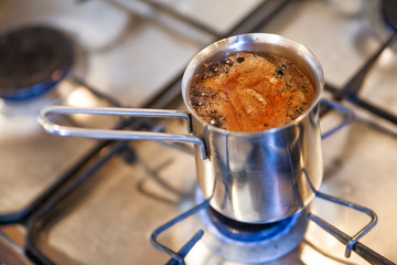 Coffee is brewed in a cezve on gas stove. Hot beverage in metal turka.
