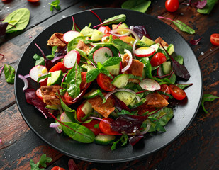 Traditional fattoush salad on a plate with pita croutons, cucumber, tomato, red onion, vegetables mix and herbs