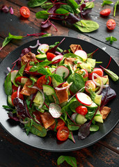 Traditional fattoush salad on a plate with pita croutons, cucumber, tomato, red onion, vegetables mix and herbs