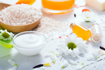 Fototapeta na wymiar aromatherapy: orange gel and extract, bath salt, cosmetic cream, organic soap and petals on white wood