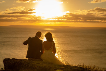 bride and groom on the beach I admire the sunset set in orange romantic light