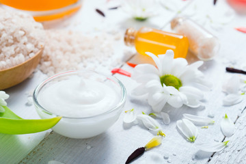 Obraz na płótnie Canvas aromatherapy: orange gel and extract, bath salt, cosmetic cream, organic soap and petals on white wood