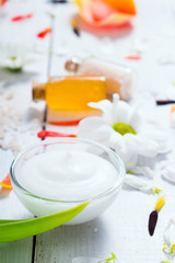 aromatherapy: orange gel and extract, bath salt, cosmetic cream, organic soap and petals on white wood