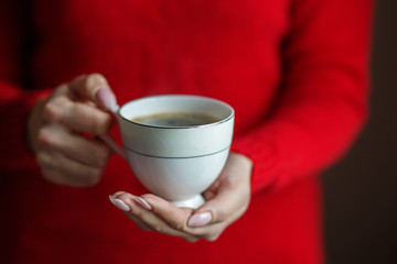 A cup of delicious hot coffee in female hands. Concept drinks, lifestyle, work, background.