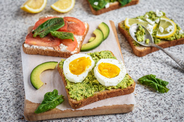 Healthy avocado and egg toasts. Toast, avocado, egg, tomatoes, spinach, cheese Feta, lemon. Organic healthy food. Clean healthy eating
