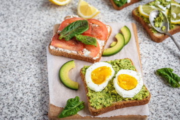 Healthy avocado and egg toasts. Toast, avocado, egg, tomatoes, spinach, cheese Feta, lemon. Organic healthy food. Clean healthy eating