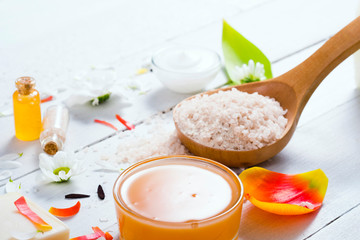aromatherapy: orange gel and extract, bath salt, cosmetic cream, organic soap and petals on white wood