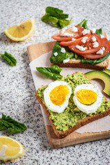 Healthy avocado and egg toasts. Toast, avocado, egg, tomatoes, spinach, cheese Feta, lemon. Organic healthy food. Clean healthy eating