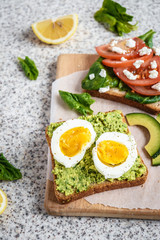 Healthy avocado and egg toasts. Toast, avocado, egg, tomatoes, spinach, cheese Feta, lemon. Organic healthy food. Clean healthy eating