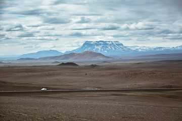 Typical ring road view with empty road and snowy mountains and one lonely car in Iceland in summer