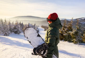 Fotobehang Meisje snowboarder staat met snowboard op de top van de berg. Skigebied © Piotr Golemo