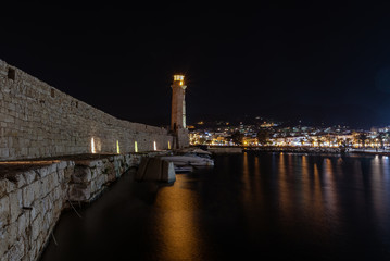 Fototapeta premium Fortress wall and old lighthouse during the night in port of Rethymno town, Crete island, Greece