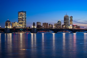 Fototapeta na wymiar Boston skyline at dusk from cambridge with longfellow bridge and frozen charles river