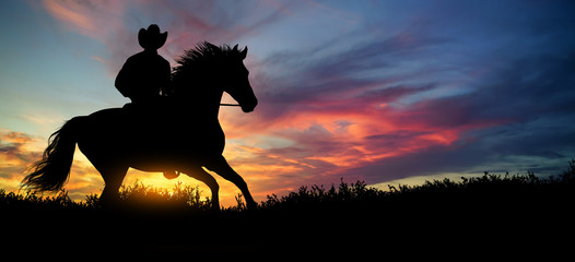 A silhouette of a cowboy and horse at sunset
