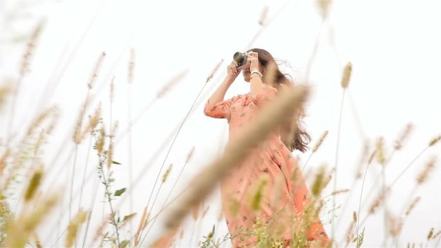 The girl with a camera photographs nature. Beautiful brunette. Slow motion