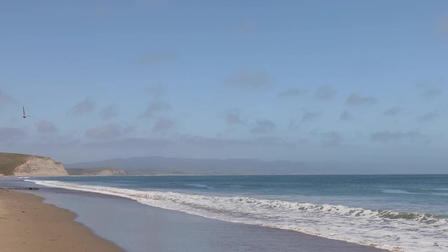 Gentle Pacific Ocean waves break on the beach along Drake’s Bay at Point Reyes National Seashore near Inverness, California. Looping.