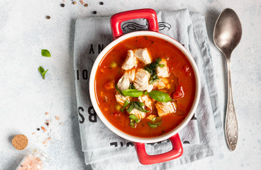 Warm tomato soup with chicken, vegetables and basil. Light concrete background. Copy space. Top view. 