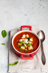 Warm tomato soup with chicken, vegetables and basil. Light concrete background. Copy space. Top view. 