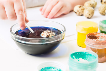 Child hand with plastic back painting eggs in blue