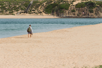 Fototapeta na wymiar Barefooted man walking on the sandy beach. Nature scenery.