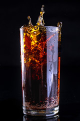 Dropping ice into a glass with a cold drink. Splash of drink in the bar.