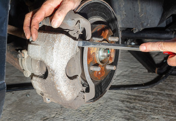 Gently using screwdriver to remove caliper from bracket  while replacing worn disk brakes 
