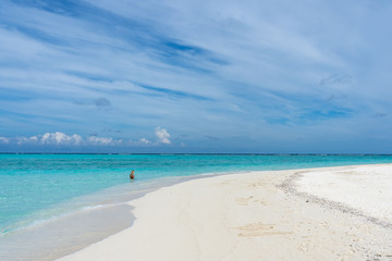 Sandbank with an unrecognized young woman in background in Maldives.  