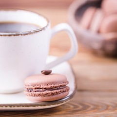 Black coffee and dessert chocolate macaroons with coffee bean on a wooden background