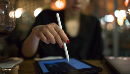 young adult artist girl drawing illustrations sketches on pro tablet with stylus at cafe