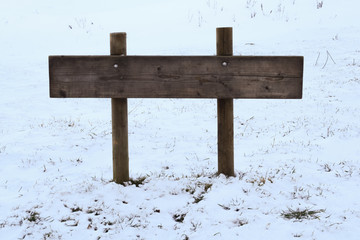 Naklejka premium Wooden pointer on the background of the winter landscape. Copy space