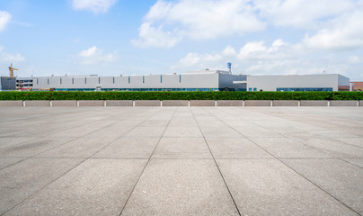 Empty square floor tiles and modern factory buildings and warehouses..