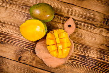 Cutting board with chopped mango fruit on a wooden table. Top view