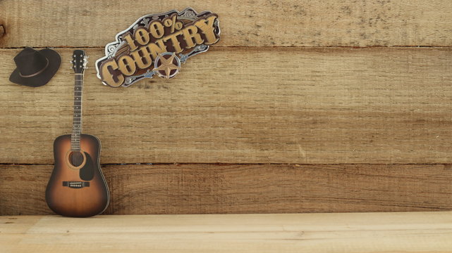 100% country sign next to a guitar and cowboy hat with writing space